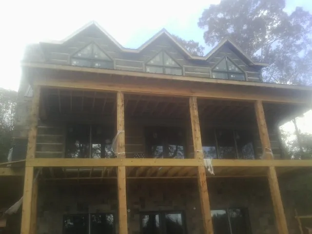 Dormers and porch framing on a large log home under construction — Roof Coating work by our crew in Harrisville